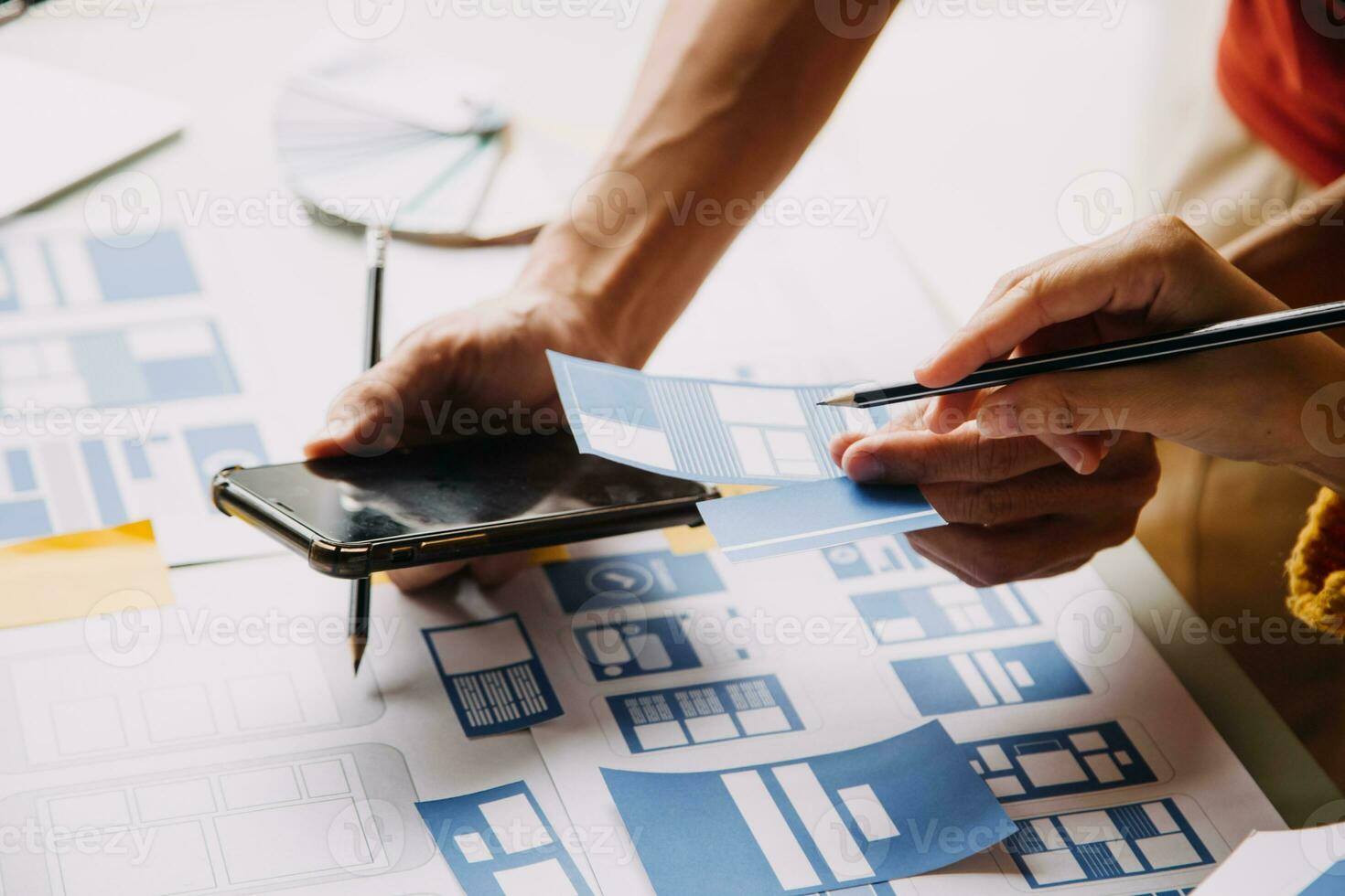 Close up ux developer and ui designer brainstorming about mobile app interface wireframe design on table with customer breif and color code at modern office.Creative digital development agency photo