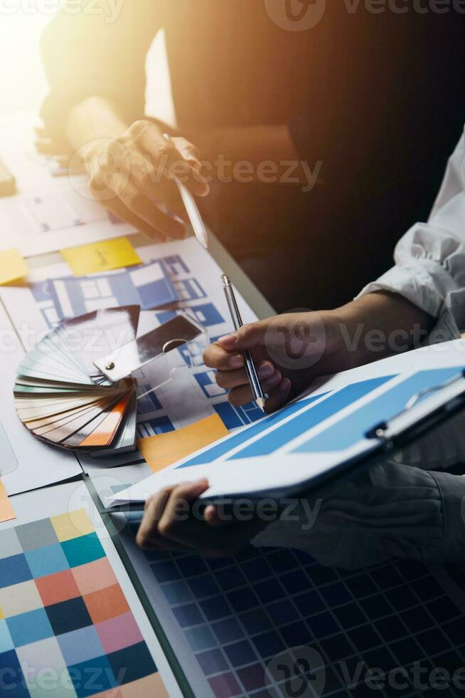 Close up ux developer and ui designer brainstorming about mobile app interface wireframe design on table with customer breif and color code at modern office.Creative digital development agency photo