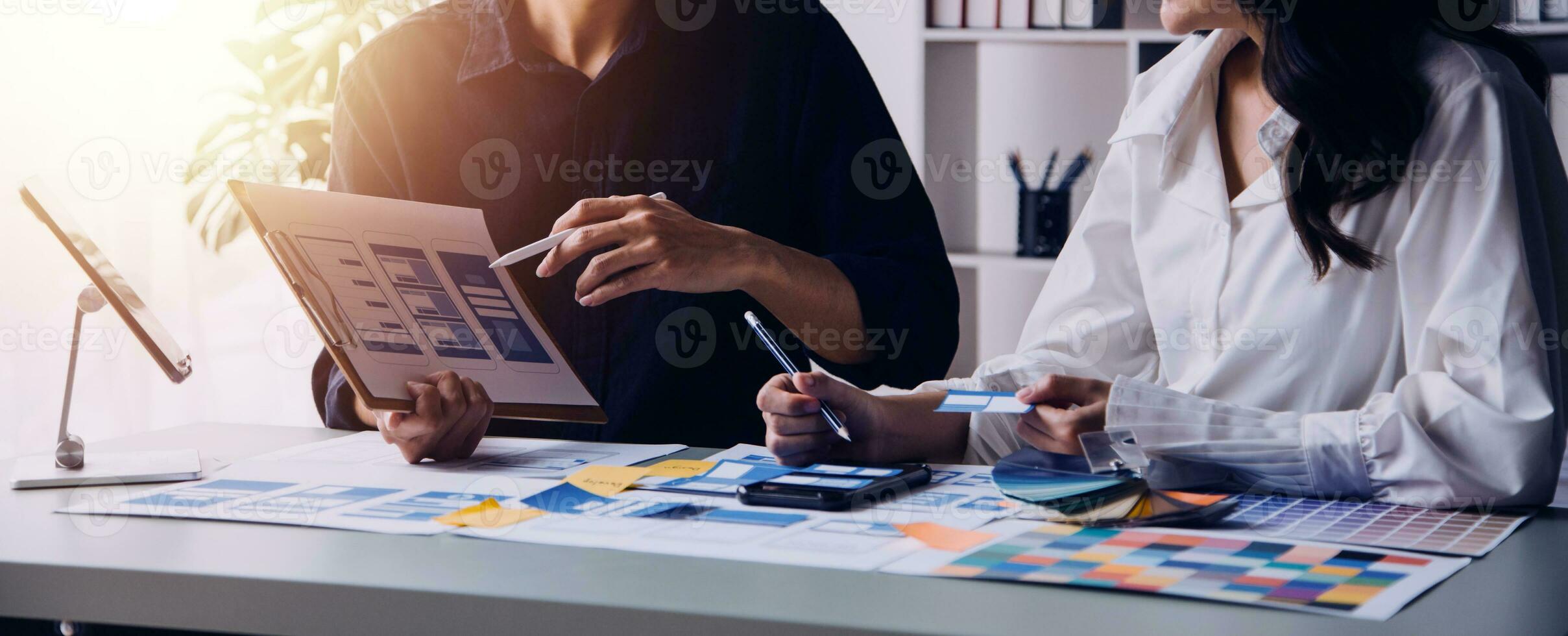 Close up ux developer and ui designer brainstorming about mobile app interface wireframe design on table with customer breif and color code at modern office.Creative digital development agency photo