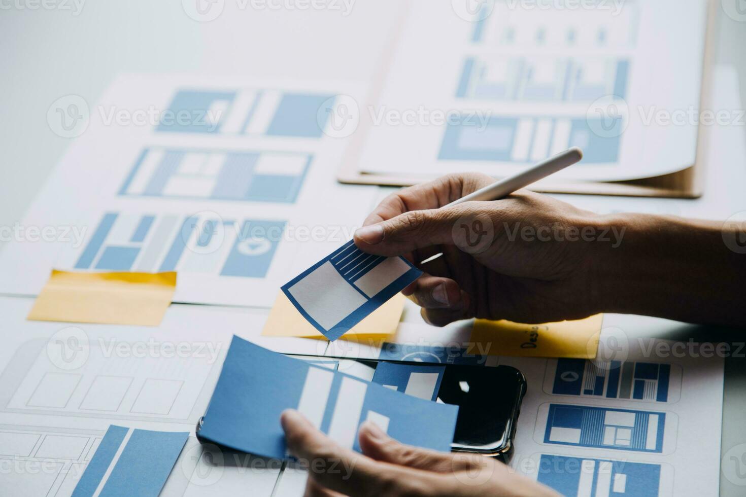 Close up ux developer and ui designer brainstorming about mobile app interface wireframe design on table with customer breif and color code at modern office.Creative digital development agency photo