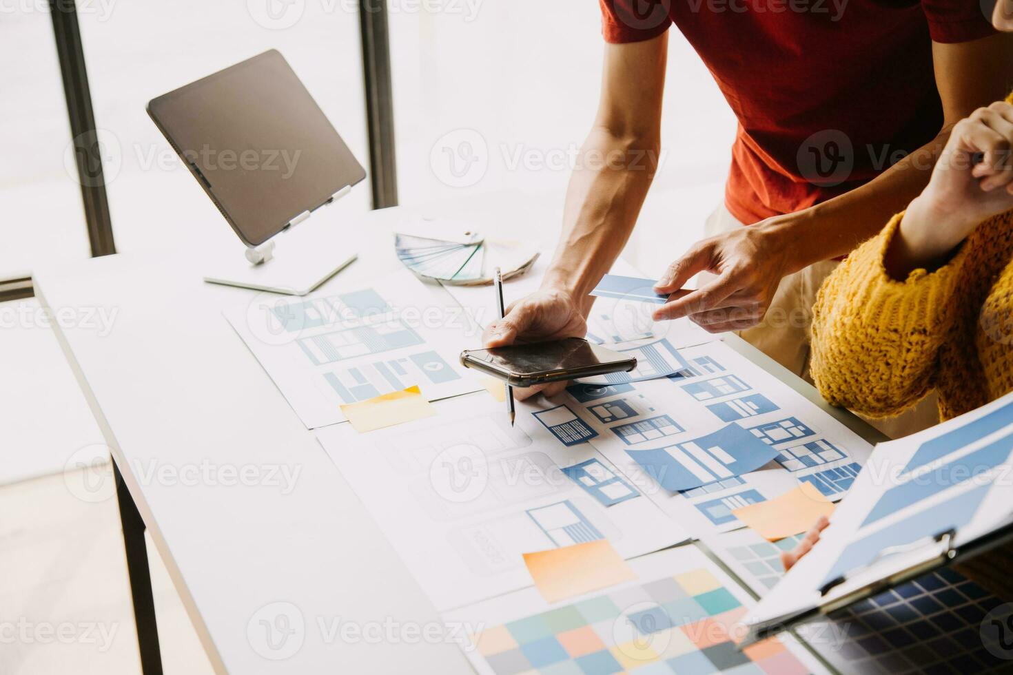 Close up ux developer and ui designer brainstorming about mobile app interface wireframe design on table with customer breif and color code at modern office.Creative digital development agency photo