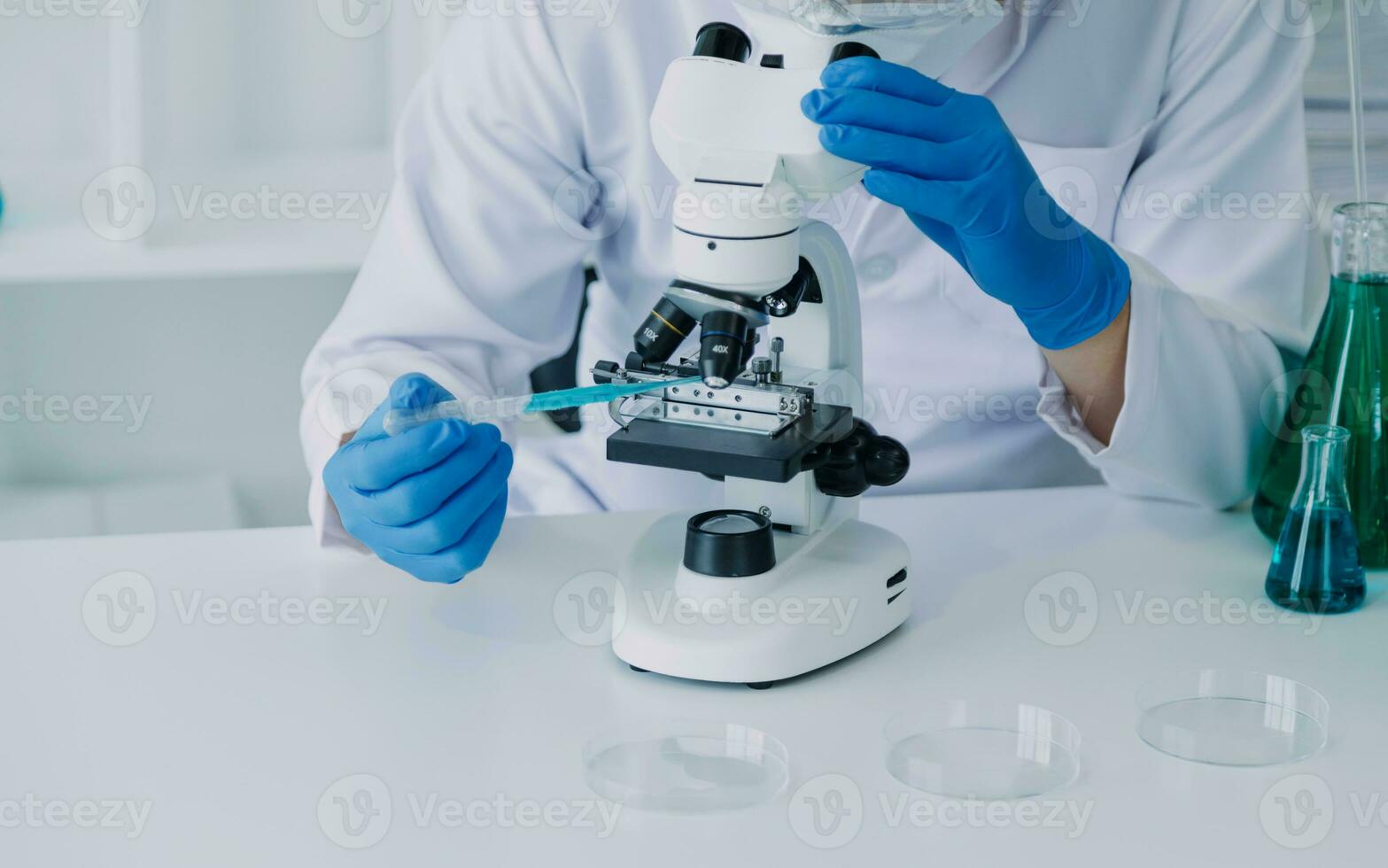 medical or scientific researcher researching and experimenting Multi-colored solution, vial and microscope In the laboratory or in the laboratory by wearing blue gloves and white clothing completely. photo