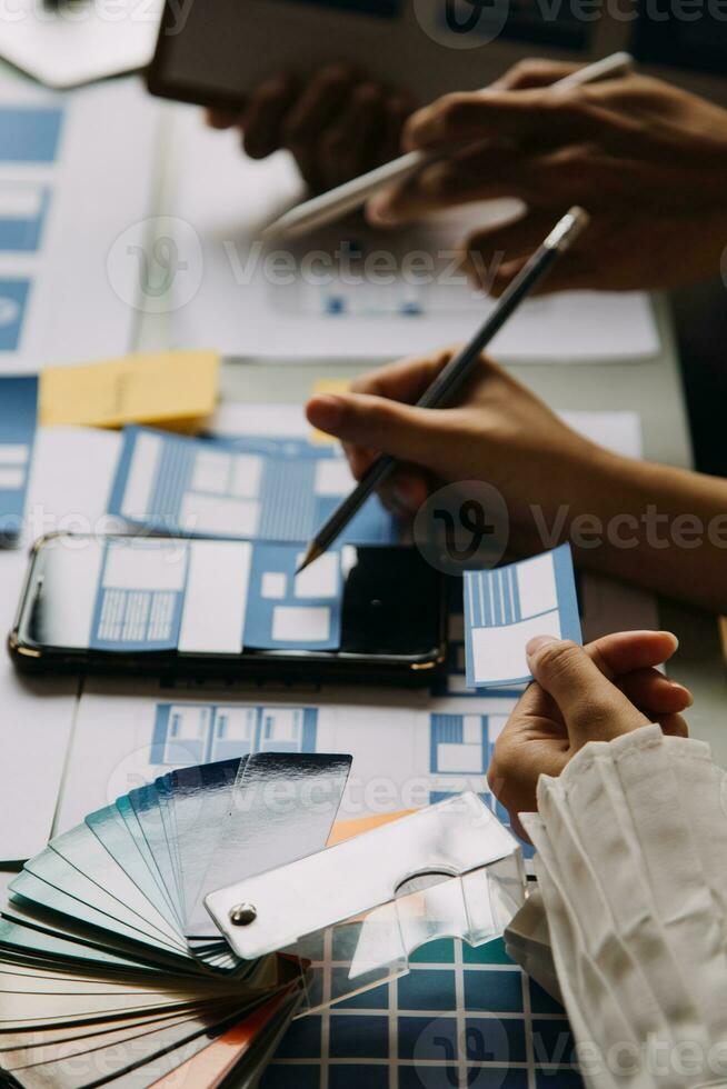 Close up ux developer and ui designer brainstorming about mobile app interface wireframe design on table with customer breif and color code at modern office.Creative digital development agency photo