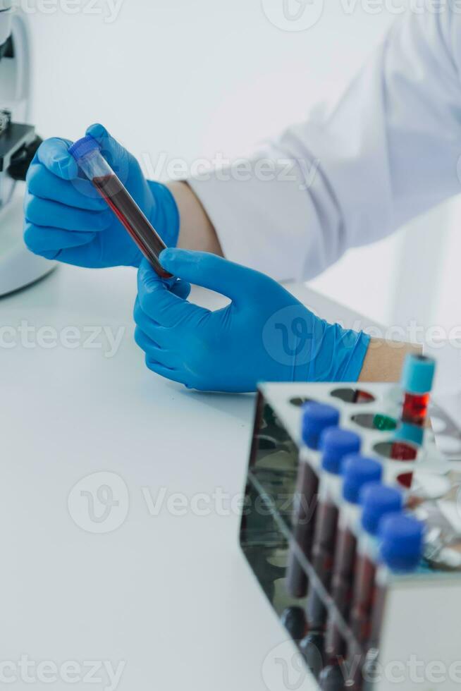 medical or scientific researcher researching and experimenting Multi-colored solution, vial and microscope In the laboratory or in the laboratory by wearing blue gloves and white clothing completely. photo