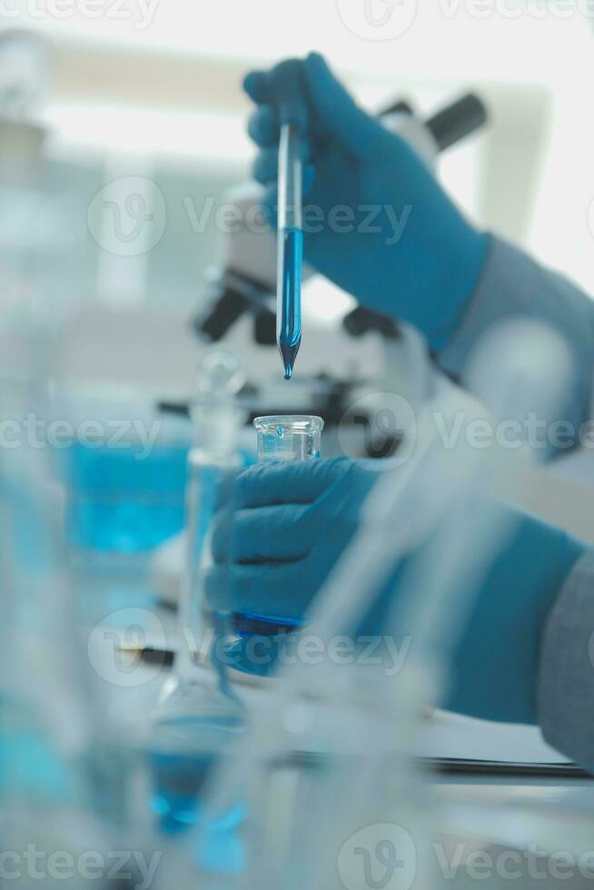biochemical research scientist team working with microscope for coronavirus vaccine development in pharmaceutical research labolatory, selective focus photo