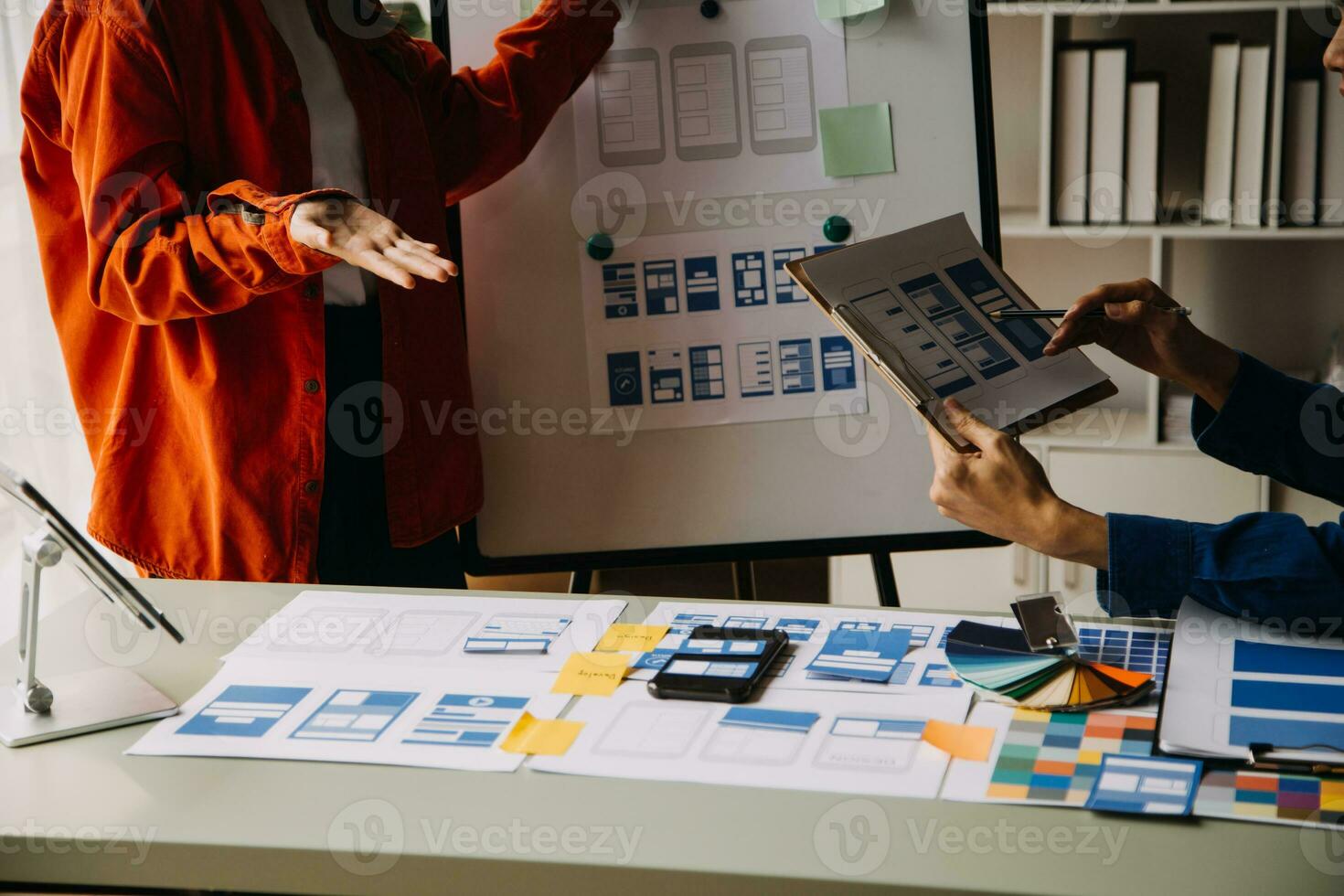 Close up ux developer and ui designer brainstorming about mobile app interface wireframe design on table with customer breif and color code at modern office.Creative digital development agency photo