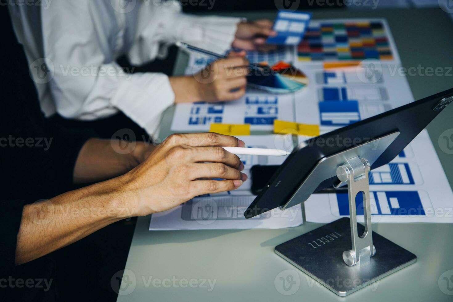 Close up ux developer and ui designer brainstorming about mobile app interface wireframe design on table with customer breif and color code at modern office.Creative digital development agency photo