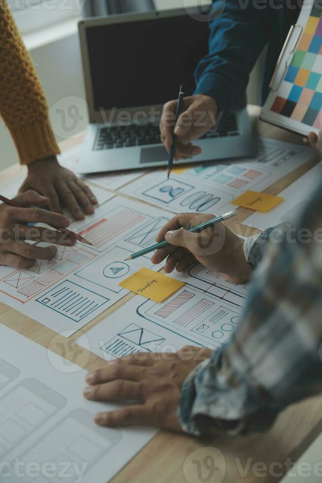 Close up ux developer and ui designer brainstorming about mobile app interface wireframe design on table with customer breif and color code at modern office.Creative digital development agency photo
