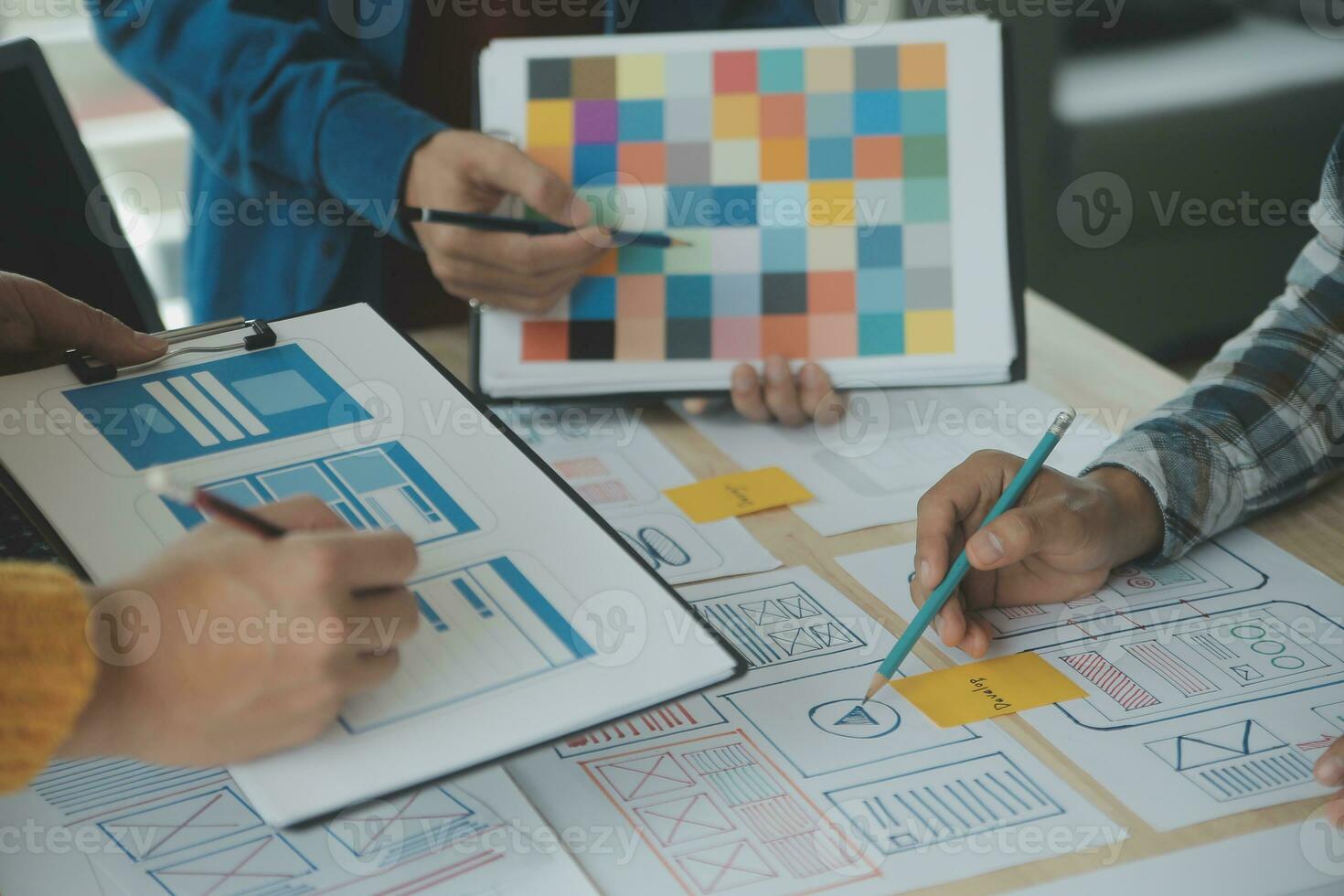 Close up ux developer and ui designer brainstorming about mobile app interface wireframe design on table with customer breif and color code at modern office.Creative digital development agency photo