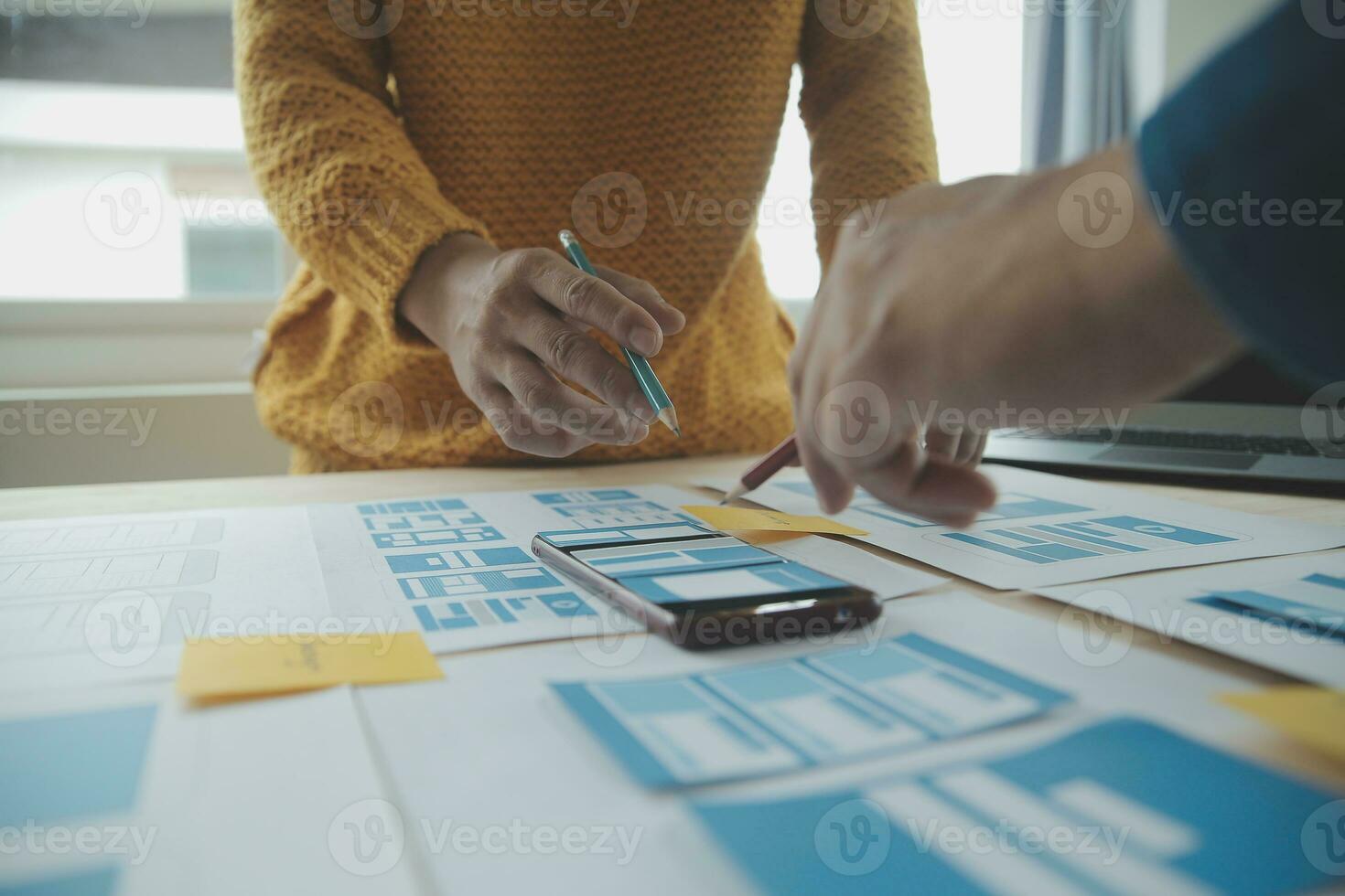 Close up ux developer and ui designer brainstorming about mobile app interface wireframe design on table with customer breif and color code at modern office.Creative digital development agency photo