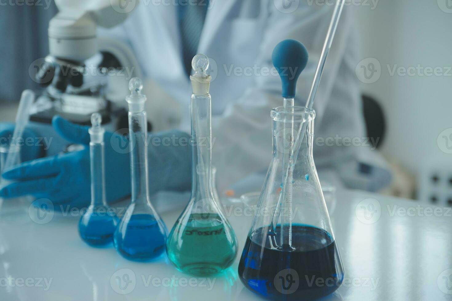 biochemical research scientist team working with microscope for coronavirus vaccine development in pharmaceutical research labolatory, selective focus photo