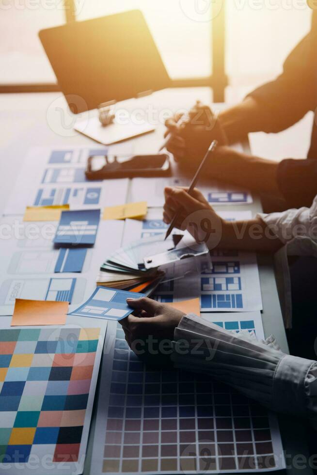 Close up ux developer and ui designer brainstorming about mobile app interface wireframe design on table with customer breif and color code at modern office.Creative digital development agency photo