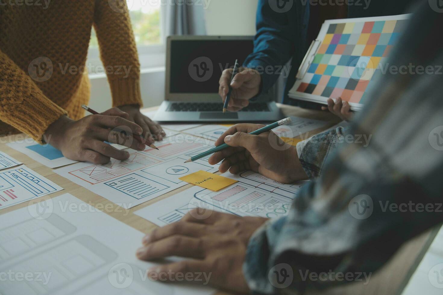 Close up ux developer and ui designer brainstorming about mobile app interface wireframe design on table with customer breif and color code at modern office.Creative digital development agency photo