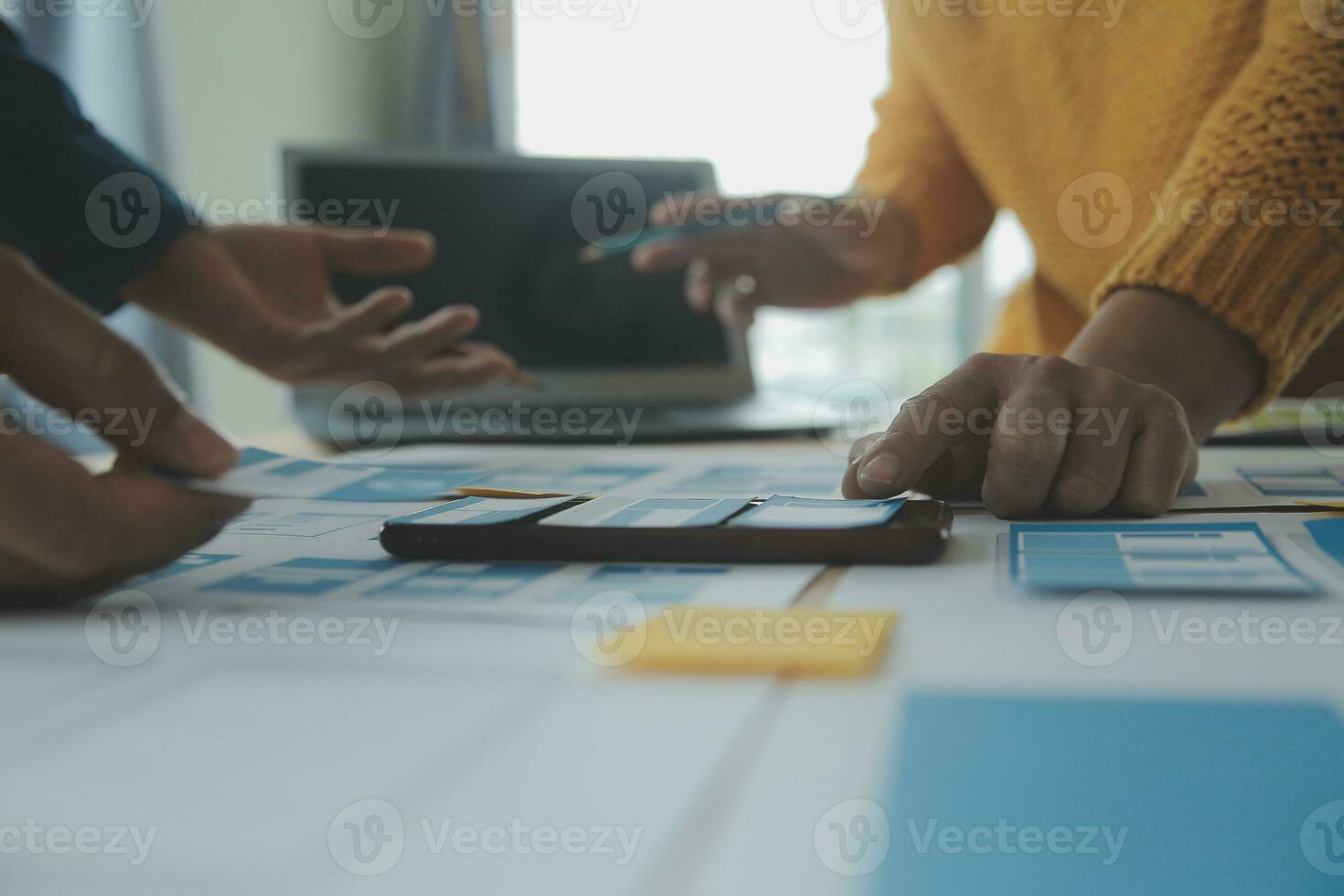 Close up ux developer and ui designer brainstorming about mobile app interface wireframe design on table with customer breif and color code at modern office.Creative digital development agency photo