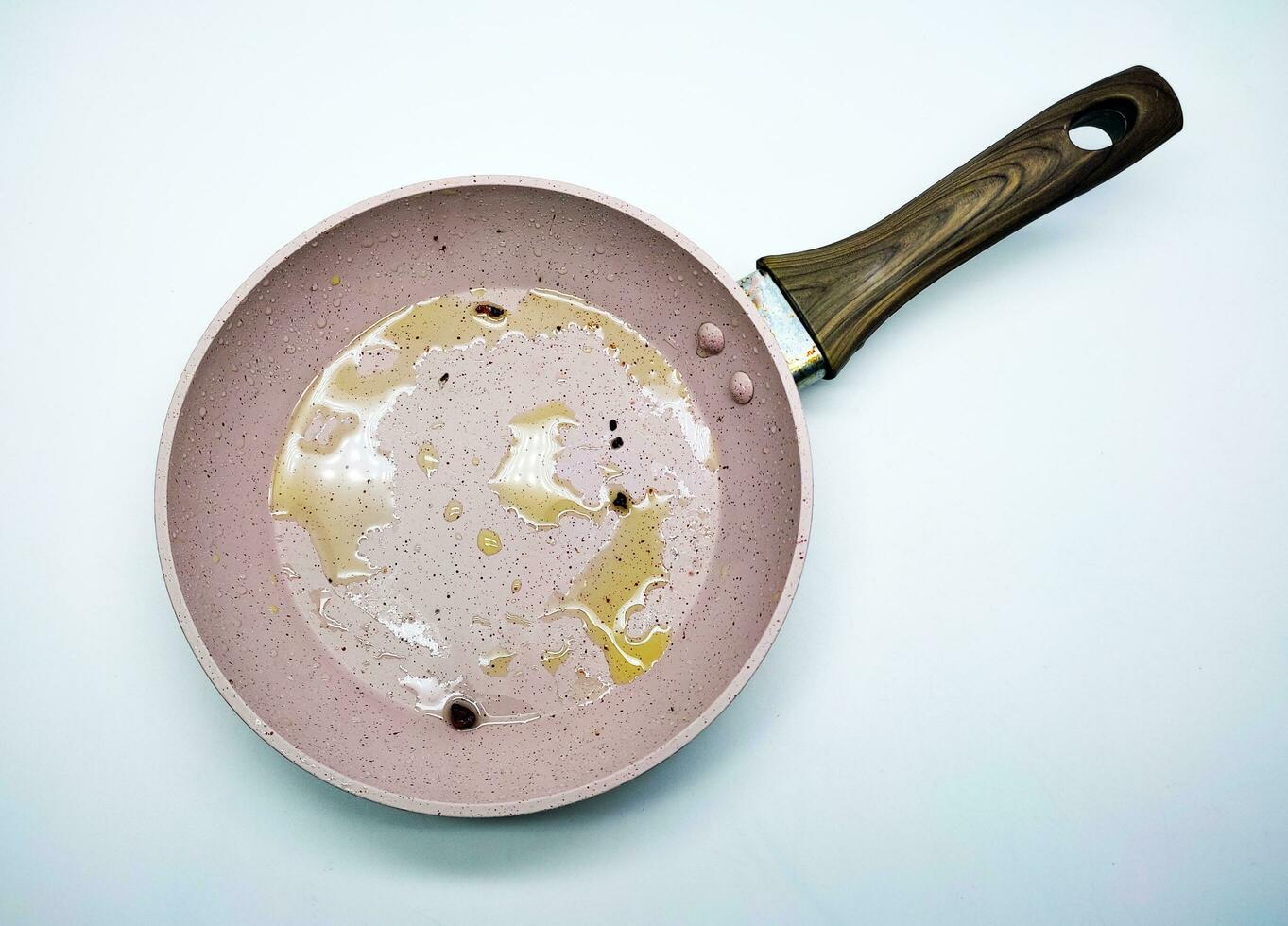 pink pan after use cooking with leftover cooking oil seen from above isolated on white background photo