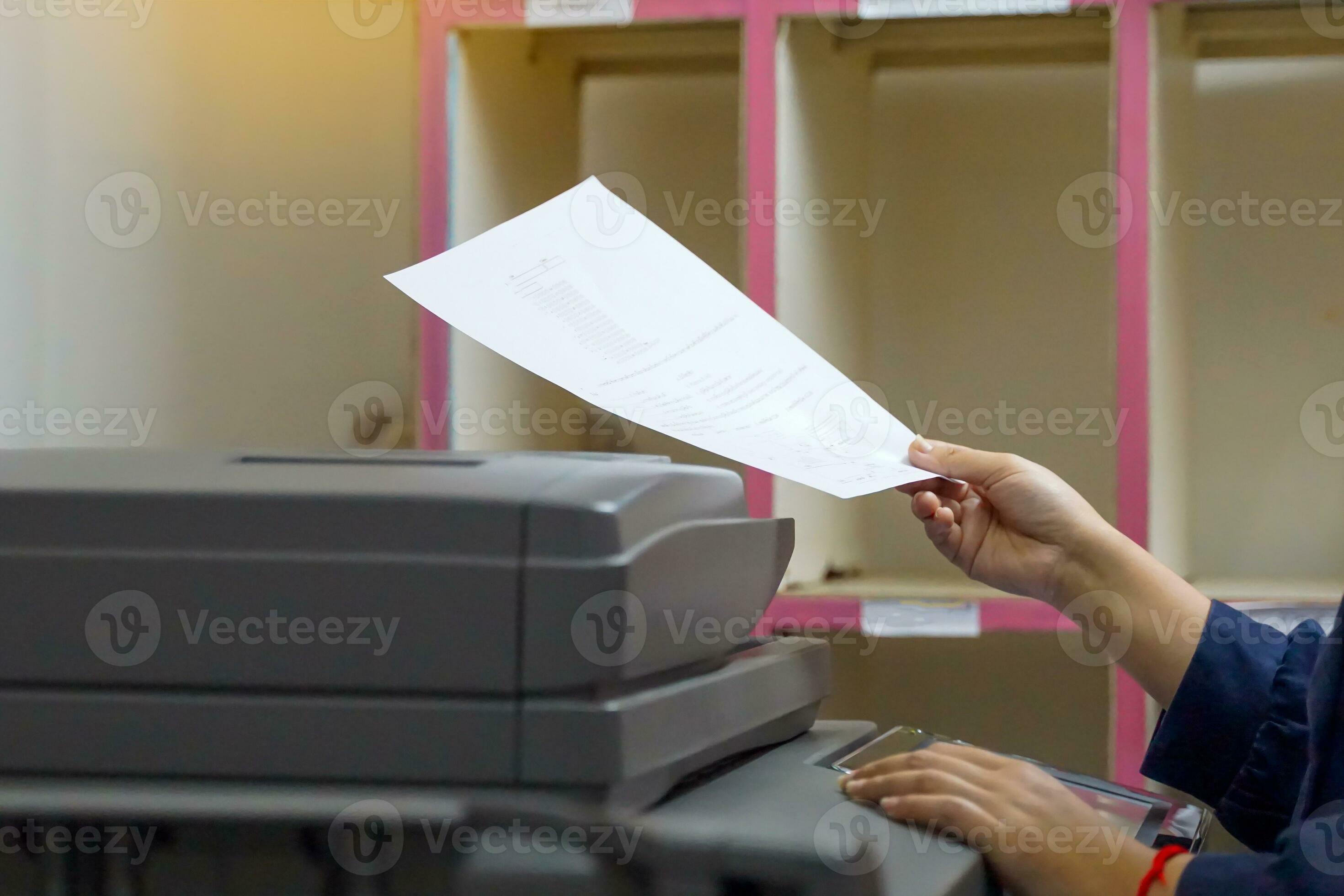 The secretary uses a copier to copy documents into a file to store in a