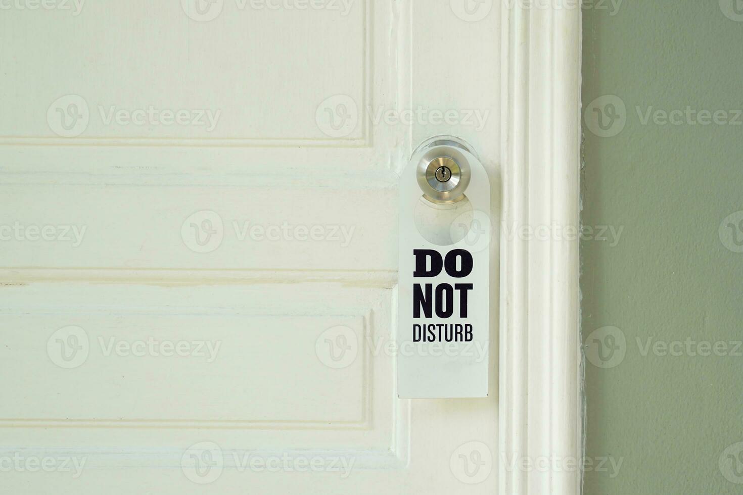 A white Do Not Disturb sign hangs on the doorknob outside the room, reminding the owner of the room that he prefers privacy rather than welcoming outsiders. photo