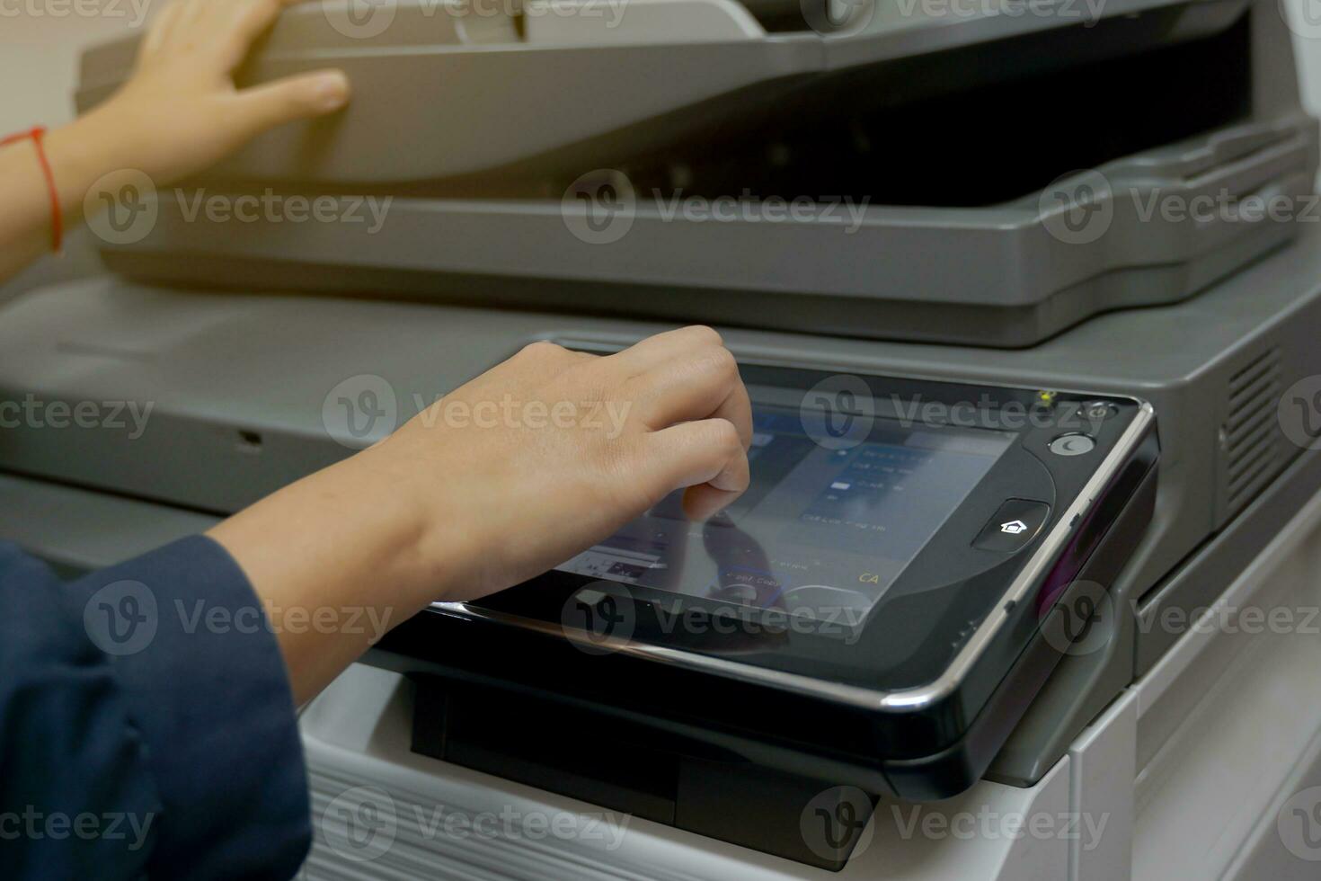 The secretary presses a finger on the keypad on the copier's screen to set up a print job to make multiple copies of a document. soft and selective focus photo