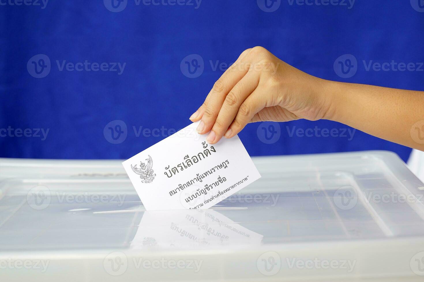 Thai people drop their ballot papers into the box to vote for members of the House of Representatives. The ballot papers are written in Thai,meaning Party-list proportional representation ballot paper photo