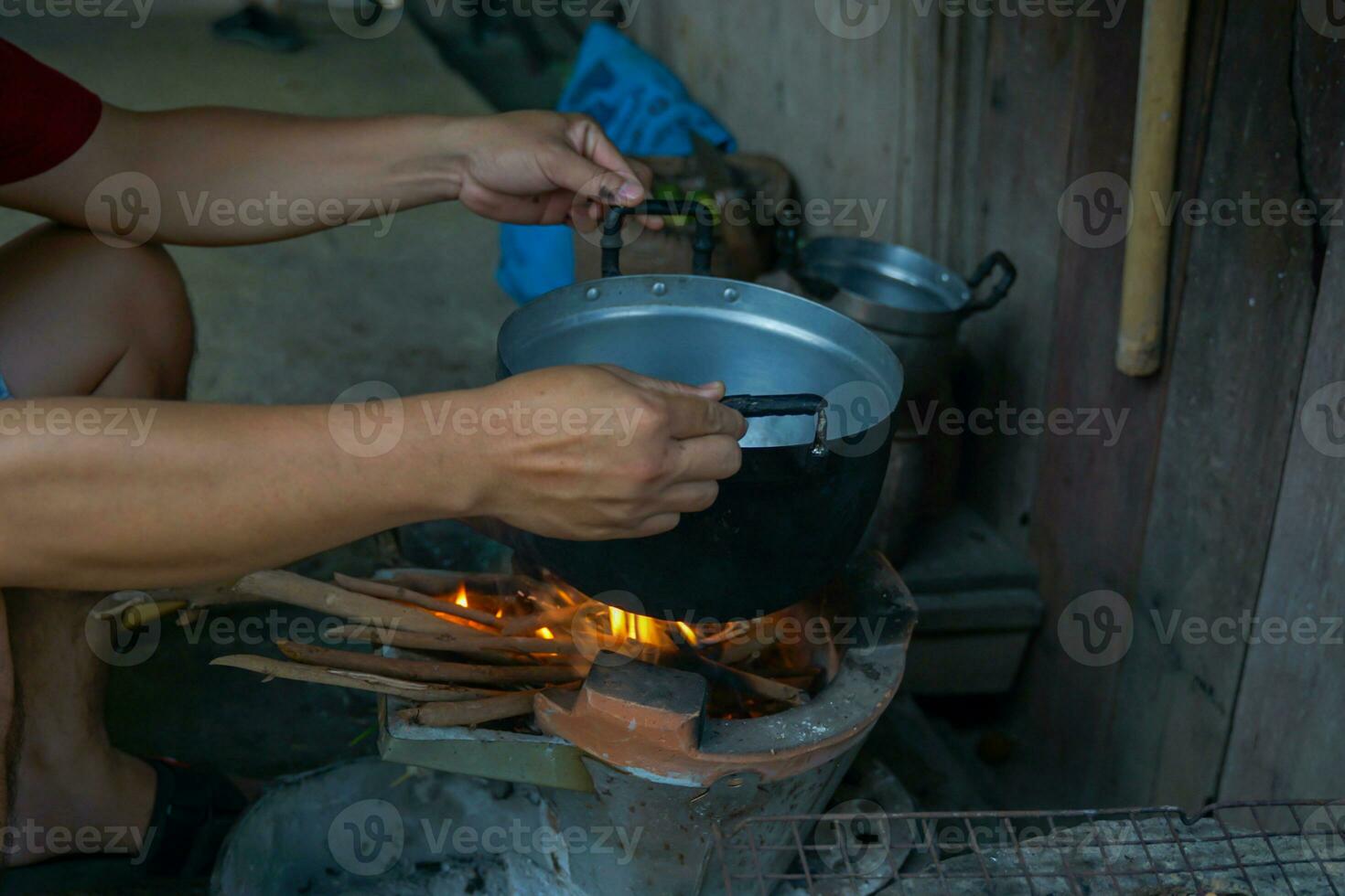 Villagers are cooking food from a wood-fired brazier. The bottom of the pot has black soot while cooking. The brazier fire is still used in rural kitchens in the North and Northeast of Thailand. photo