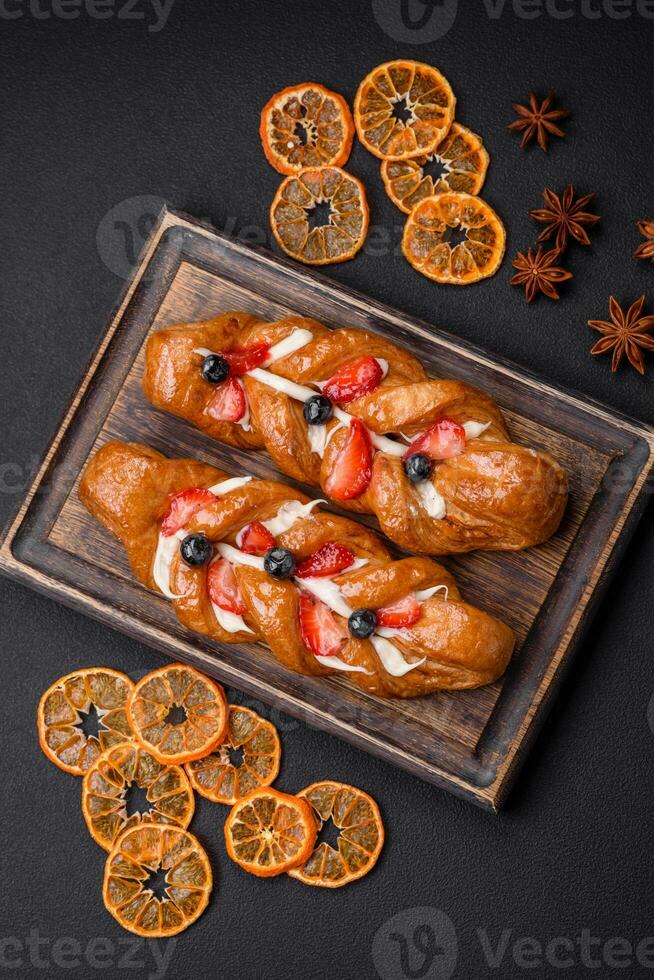 Delicious fresh crispy pastry in the form of a pigtail with strawberries and blueberries photo