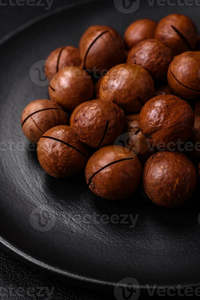 Delicious roasted macadamia nuts in shell on a dark textured background photo
