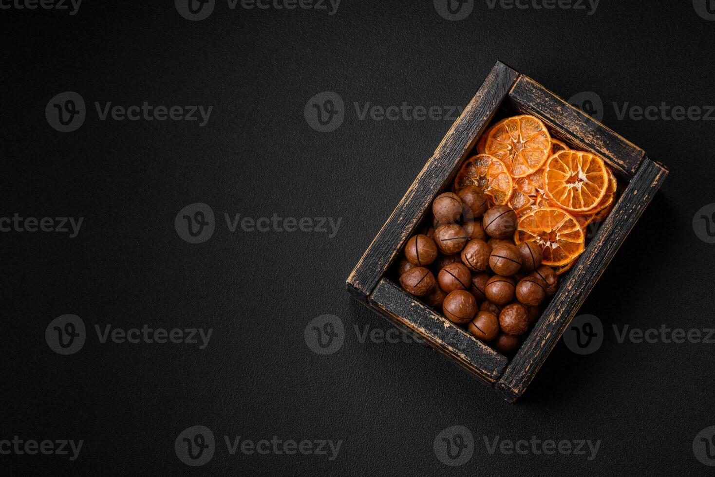 Delicious roasted macadamia nuts in shell on a dark textured background photo