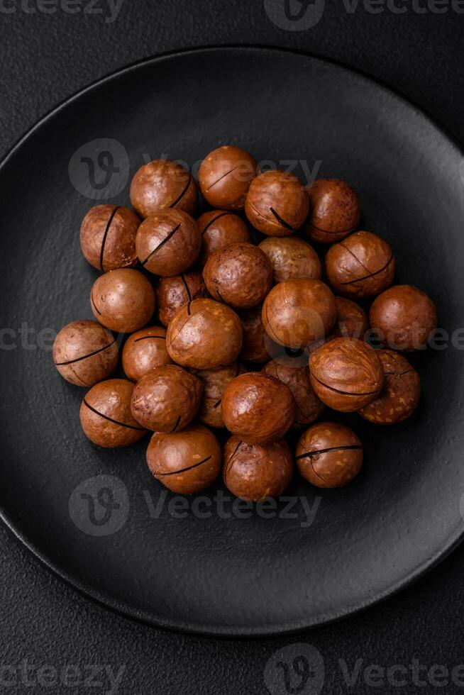 Delicious roasted macadamia nuts in shell on a dark textured background photo