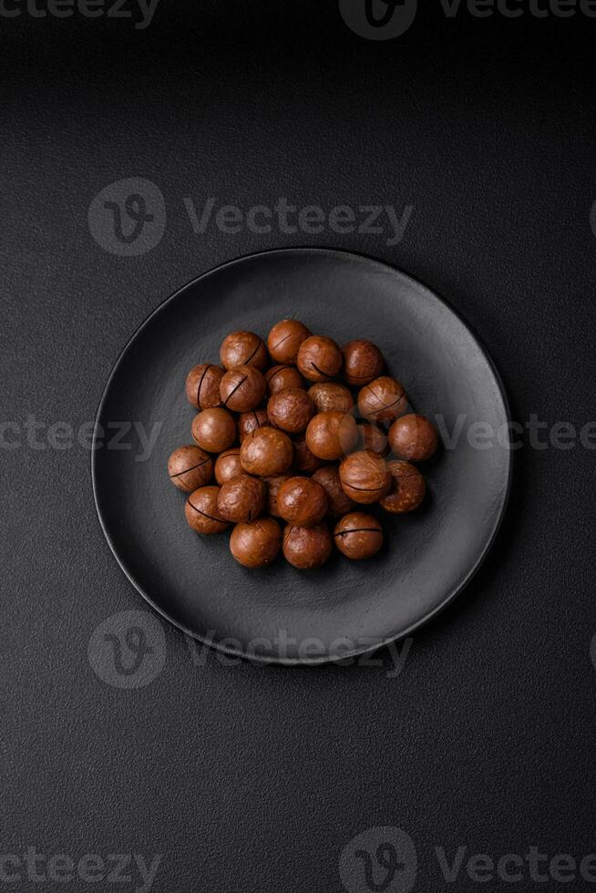 Delicious roasted macadamia nuts in shell on a dark textured background photo