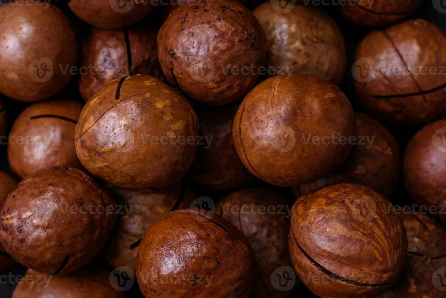 Delicious roasted macadamia nuts in shell on a dark textured background photo