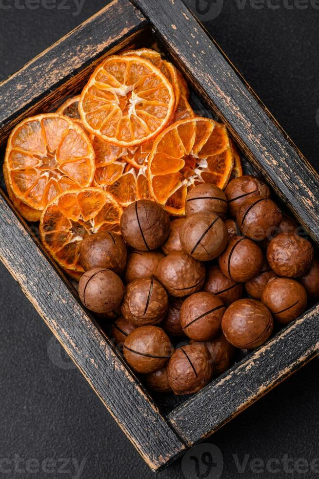 Delicious roasted macadamia nuts in shell on a dark textured background photo