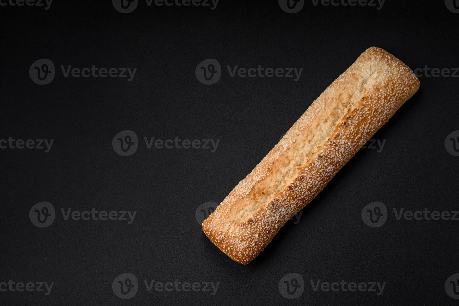 Crispy wheat flour baguette with sesame seeds on a wooden cutting board photo