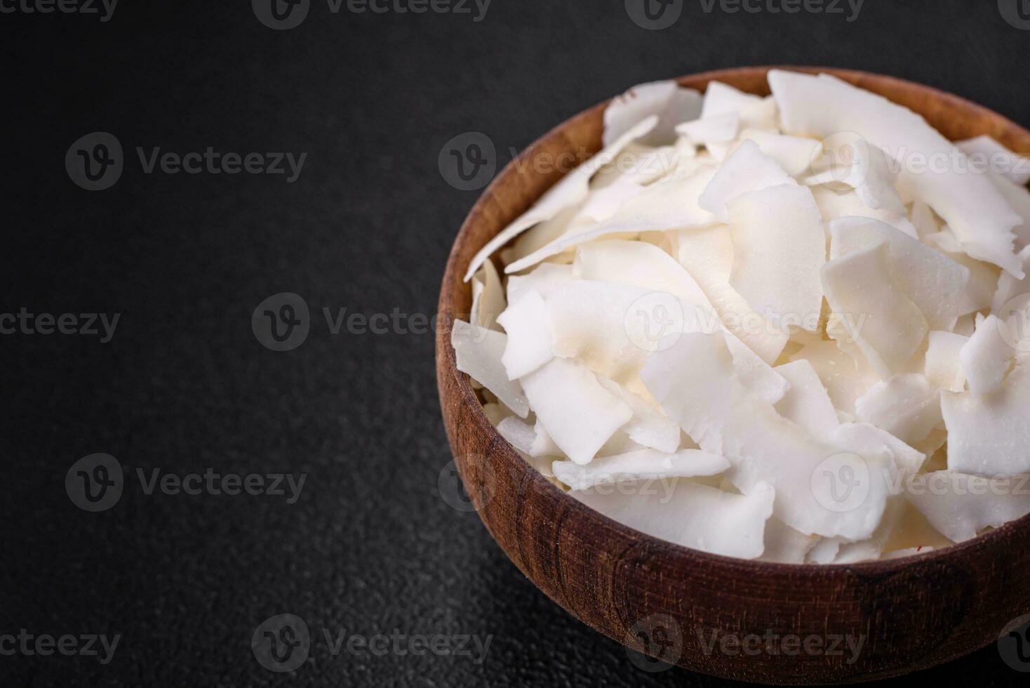 White dry coconut flakes in a wooden bowl prepared for making desserts photo