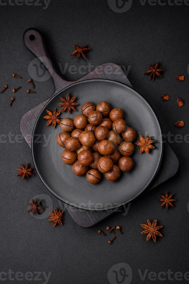 Delicious roasted macadamia nuts in shell on a dark textured background photo