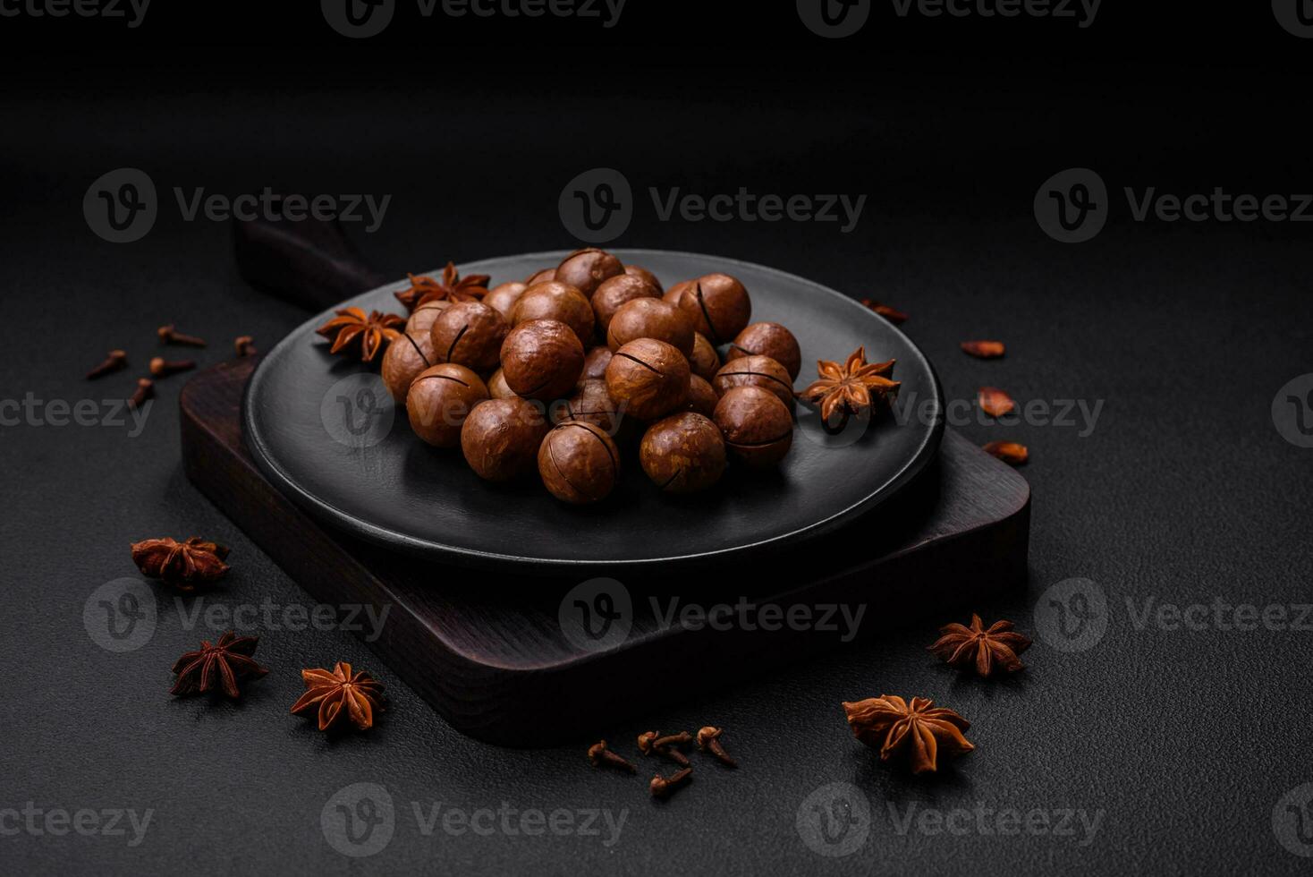 Delicious roasted macadamia nuts in shell on a dark textured background photo
