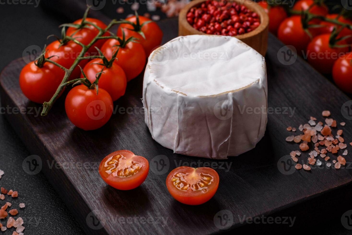 delicioso Fresco queso Brie queso en el formar de un mini cabeza con Cereza Tomates foto