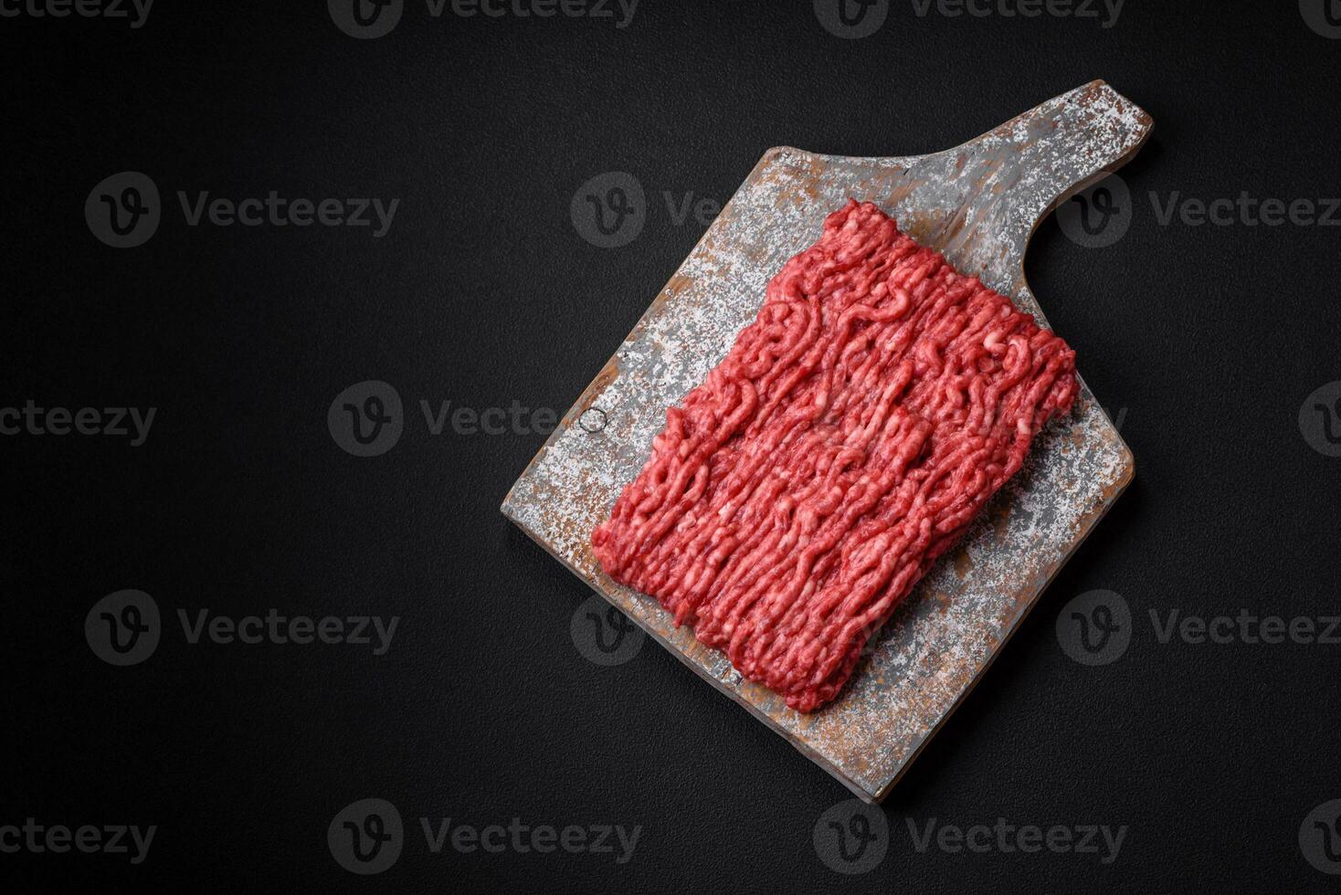 Raw ground beef or pork on a wooden cutting board with spices and salt photo