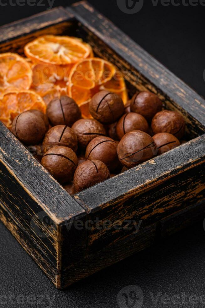 Delicious roasted macadamia nuts in shell on a dark textured background photo