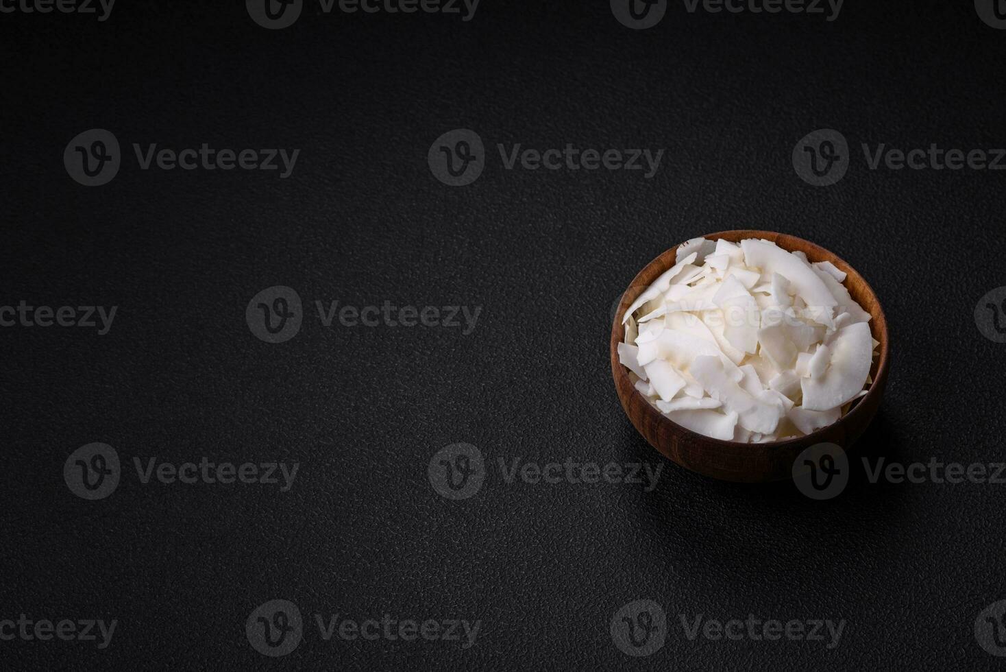 White dry coconut flakes in a wooden bowl prepared for making desserts photo