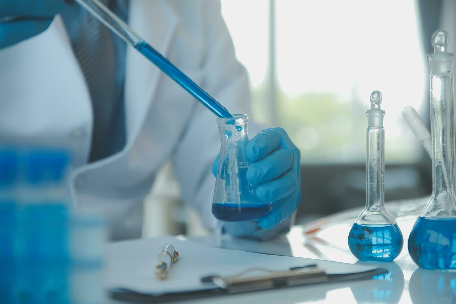 biochemical research scientist team working with microscope for coronavirus vaccine development in pharmaceutical research labolatory, selective focus photo