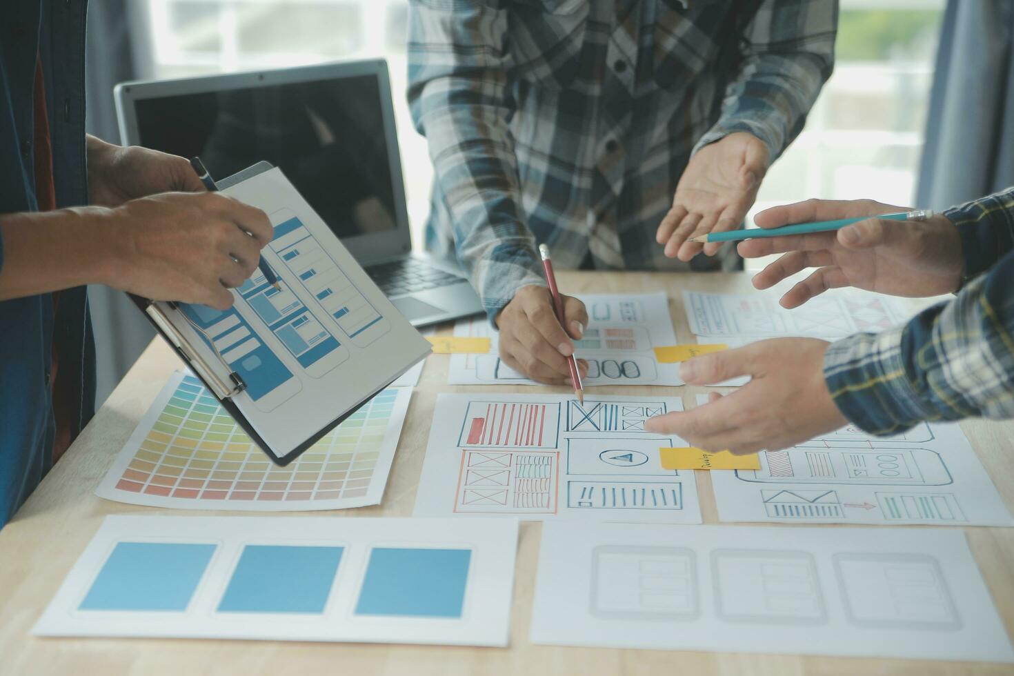 Close up ux developer and ui designer brainstorming about mobile app interface wireframe design on table with customer breif and color code at modern office.Creative digital development agency photo