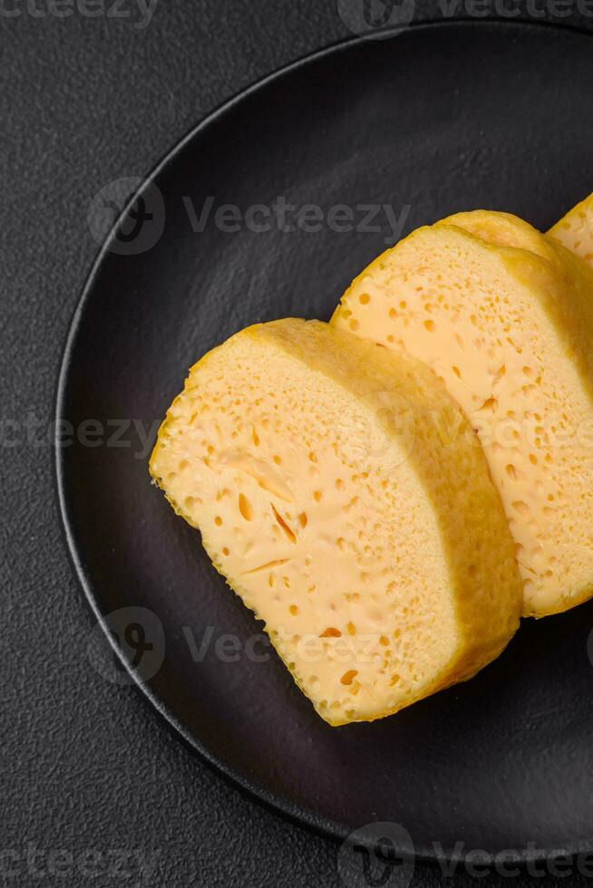 Delicious porous yellow cheese cut in large pieces on a ceramic plate photo