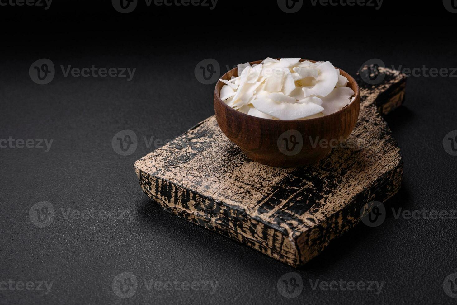White dry coconut flakes in a wooden bowl prepared for making desserts photo