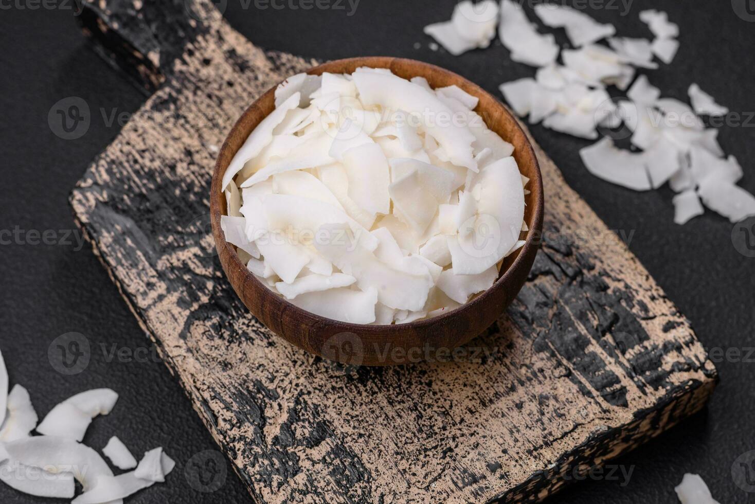 White dry coconut flakes in a wooden bowl prepared for making desserts photo