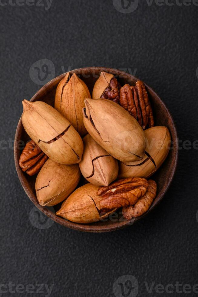 Pecan nuts in shell and peeled in a wooden round bowl photo