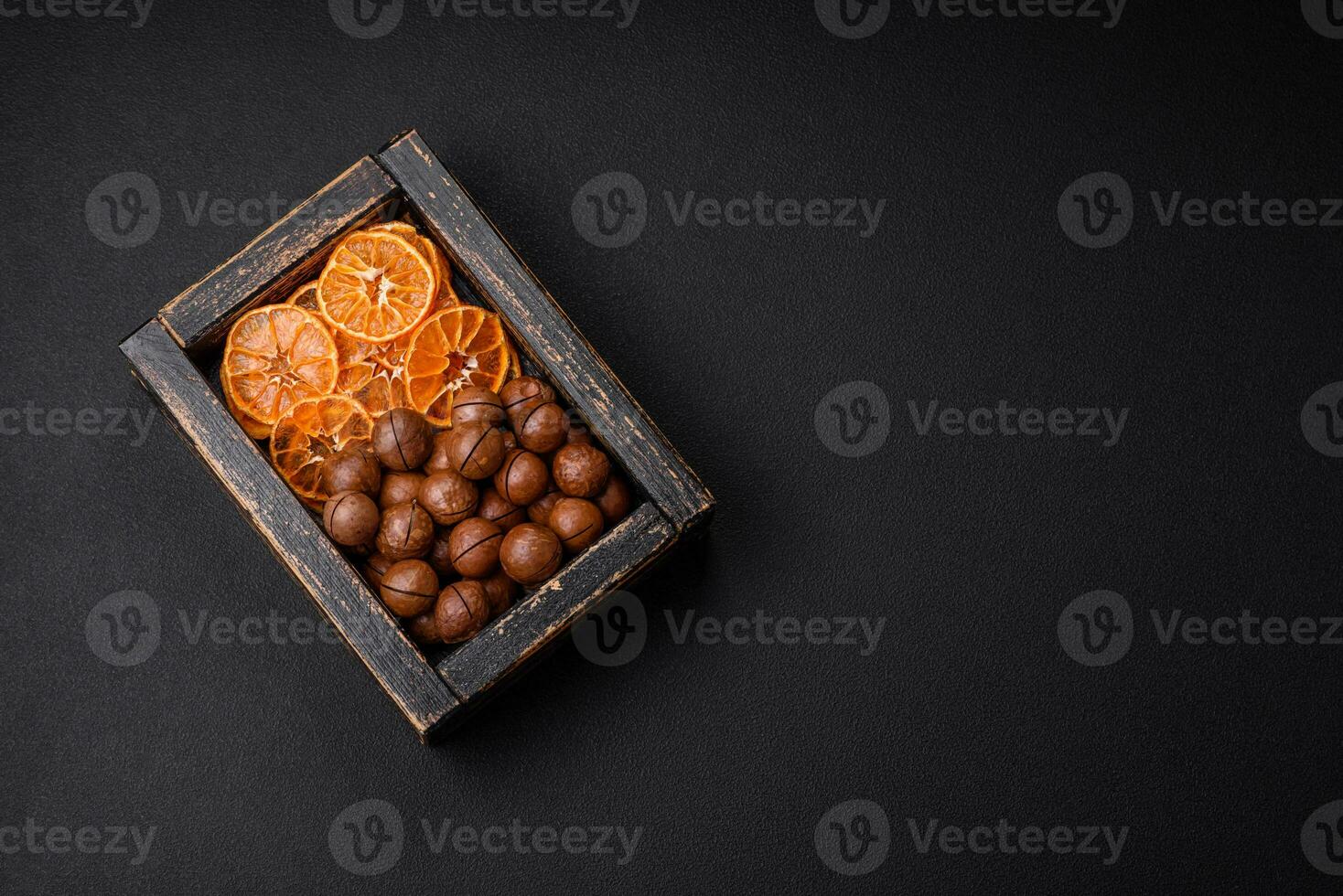 Delicious roasted macadamia nuts in shell on a dark textured background photo