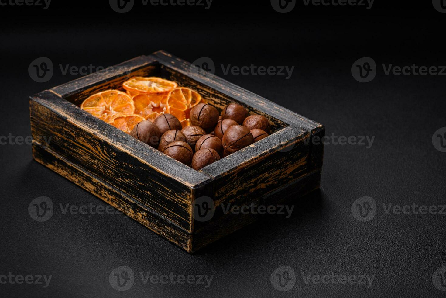 Delicious roasted macadamia nuts in shell on a dark textured background photo