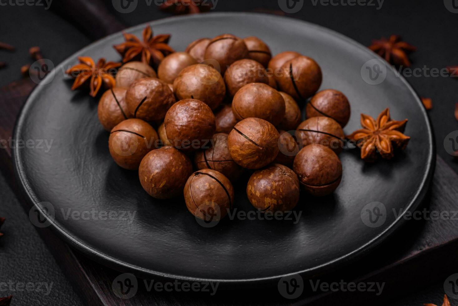 Delicious roasted macadamia nuts in shell on a dark textured background photo