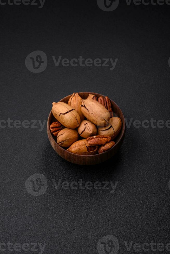 Pecan nuts in shell and peeled in a wooden round bowl photo