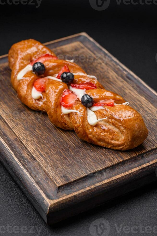 delicioso Fresco crujiente Pastelería en el formar de un coleta con fresas y arándanos foto